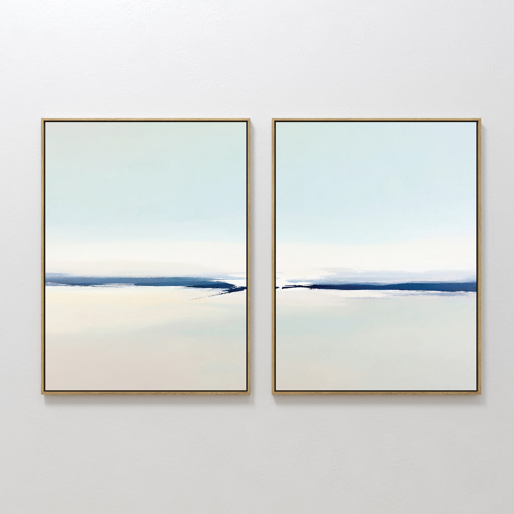 Frozen Channel - Set Of 2 features two minimalist wall art prints with thin gold frames and soft blue and off-white gradients, evoking calm water and sky—ideal for modern living room decor.