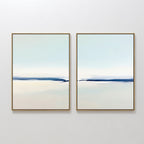Frozen Channel - Set Of 2 features two minimalist wall art prints with thin gold frames and soft blue and off-white gradients, evoking calm water and sky—ideal for modern living room decor.