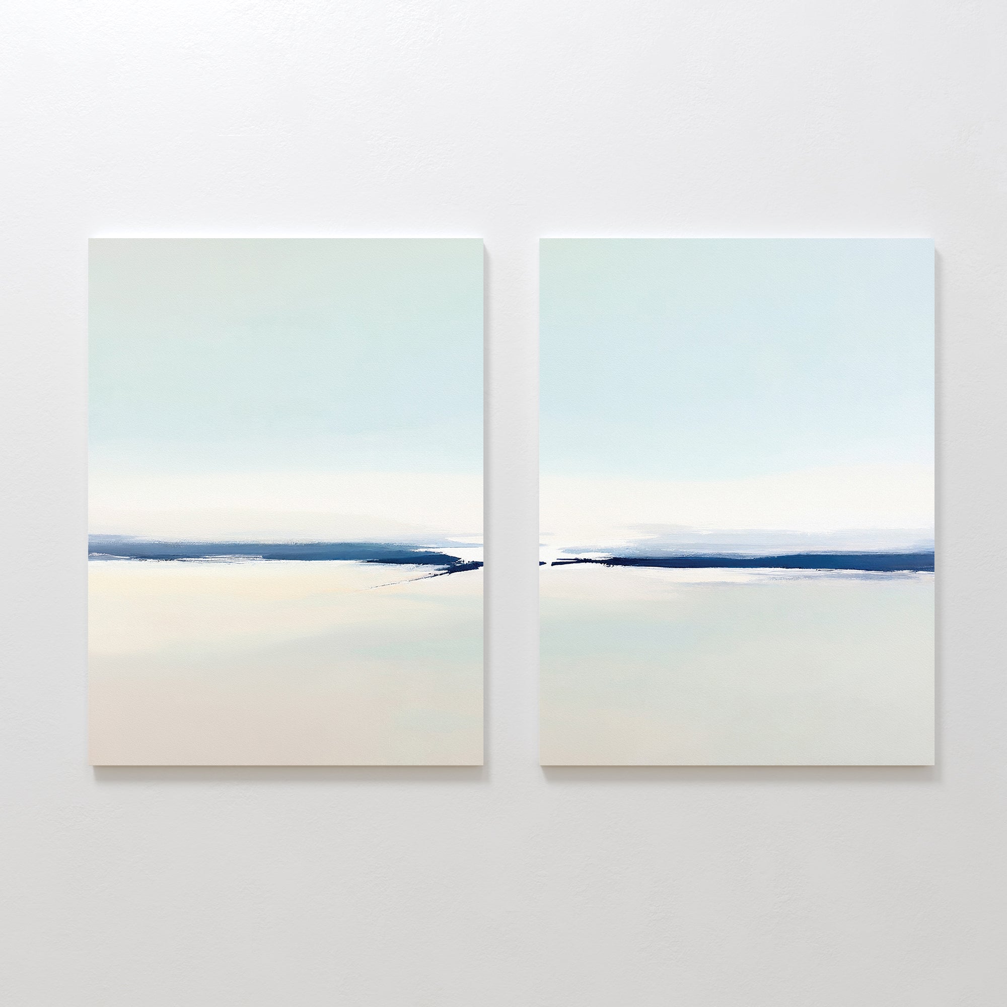 Frozen Channel - Set Of 2 features minimalist wall art with soft, blurred horizontal bands of light blue, white, and beige—ideal serene prints for modern living room decor against a white wall.