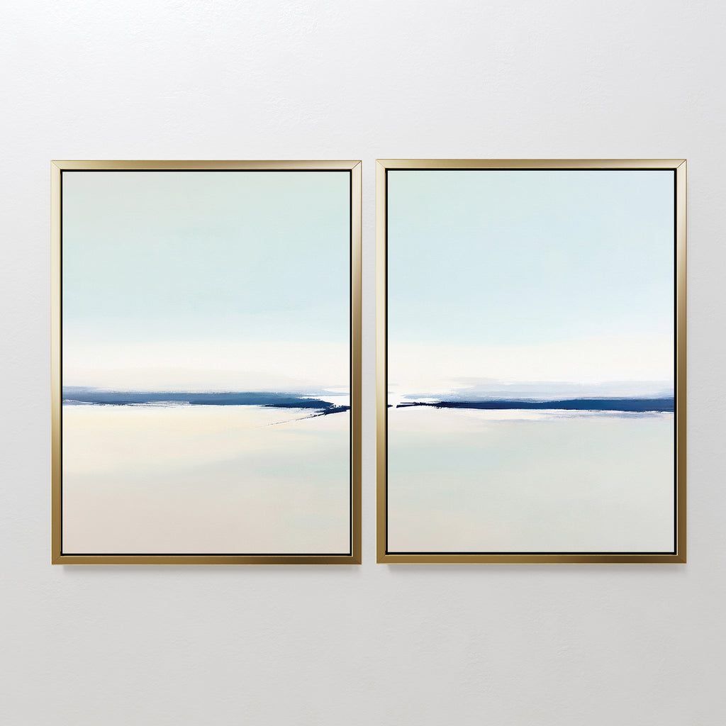 The Frozen Channel - Set Of 2 features minimalist art prints in gold frames, each displaying a calm abstract landscape with soft blue, white, and beige tones—ideal for modern living room decor.
