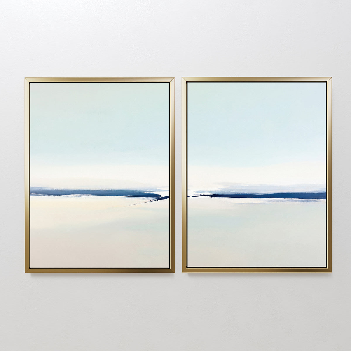 The Frozen Channel - Set Of 2 features minimalist art prints in gold frames, each displaying a calm abstract landscape with soft blue, white, and beige tones—ideal for modern living room decor.