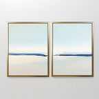 The Frozen Channel - Set Of 2 features minimalist art prints in gold frames, each displaying a calm abstract landscape with soft blue, white, and beige tones—ideal for modern living room decor.