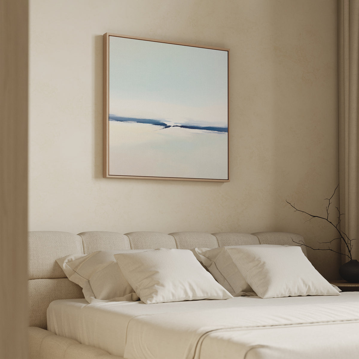 A minimalist bedroom with a beige upholstered bed, crisp white bedding, and the Frozen Channel Canvas Art - Square in soft blue and white tones hanging above the headboard. A bare branch decorates a corner.