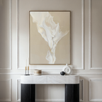 A modern entryway features a marble-topped console table, decorative objects, and the White Flame Abstract Canvas Art—an elegant cream and beige painting—set against neutral paneled walls.