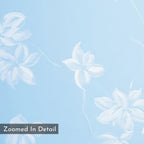 White, hand-painted floral motifs adorn a light blue background with soft brushstrokes. The Gentle Blossoms Canvas Art - Horizontal features a translucent gray label in the bottom left reading Zoomed In Detail. Ideal as wall decor.