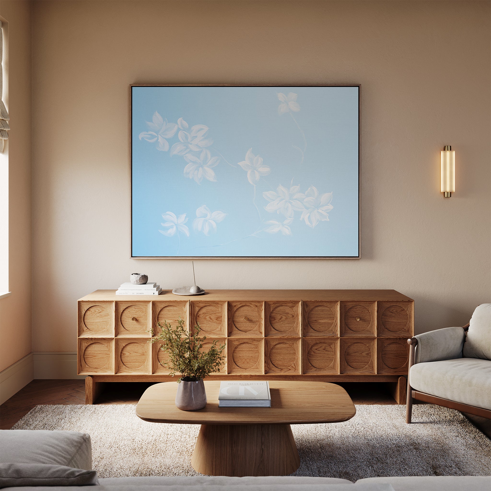 A cozy, modern living room with neutral tones features a wooden sideboard with circular patterns, the Gentle Blossoms Canvas Art - Horizontal as wall art, a beige sofa, a wooden coffee table, and a vase with flowers.