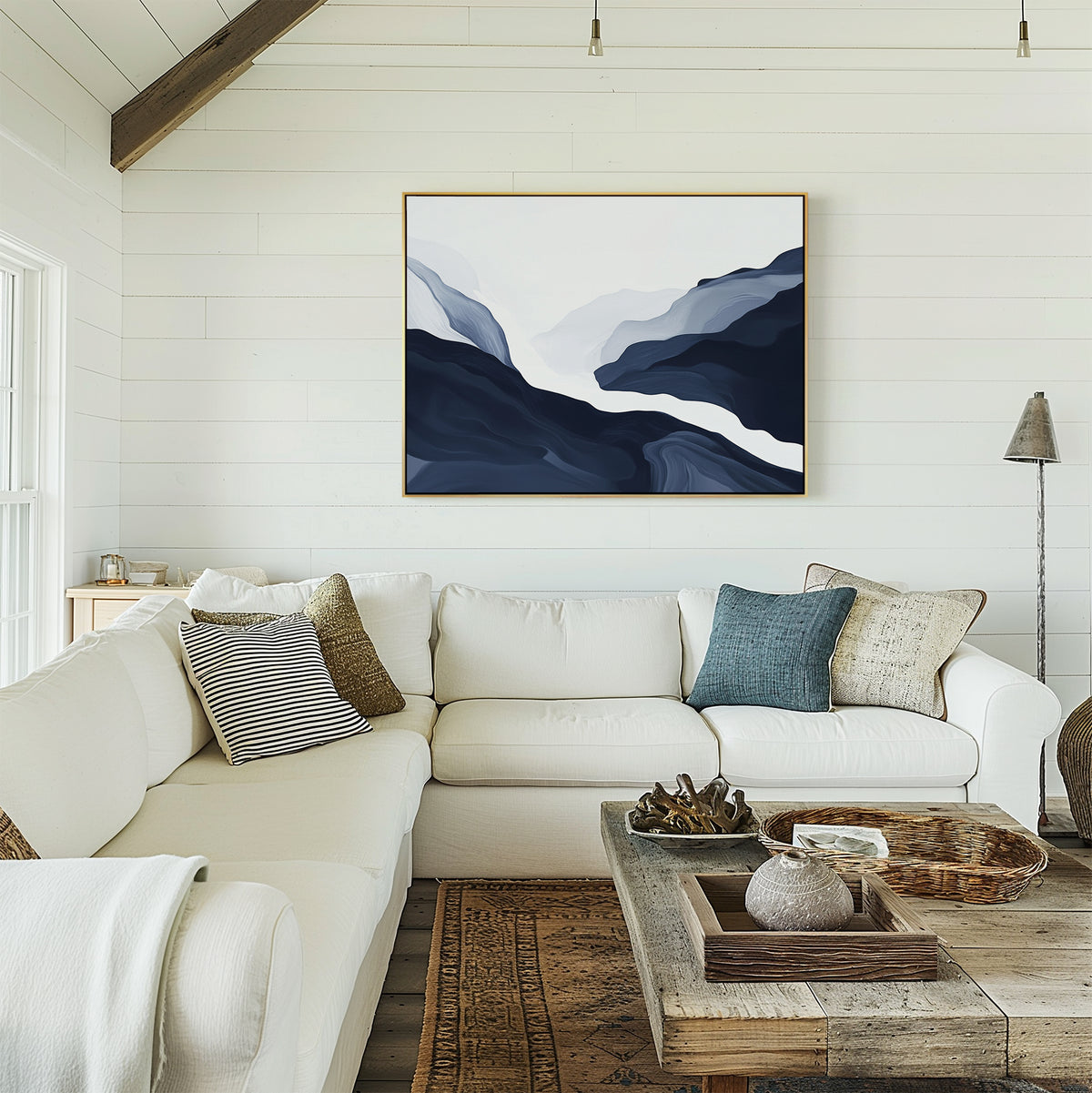 A bright, cozy living room with modern decor: a white sectional sofa, assorted pillows, a rustic wooden coffee table, and the Glacier Flow Canvas Art - Horizontal in blue and white on a shiplap wall. Natural light streams in from the left.