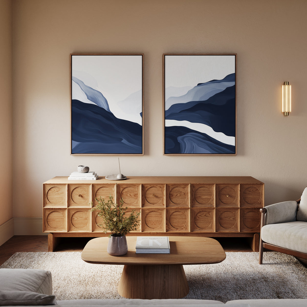 A modern living room features a wooden sideboard, a low coffee table, a white armchair, and Glacier Flow - Set Of 2 wall art in navy blue. A small plant and books decorate the space, bringing Nordic decor charm.