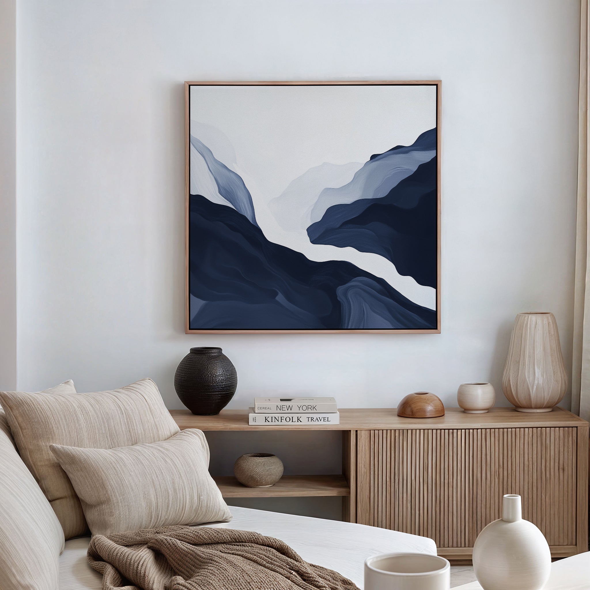 A modern, minimalist living room featuring a beige sofa, neutral pillows, wooden sideboard, decorative vases, books, and the Glacier Flow Canvas Art - Square as bold wall decor above.