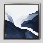 The Glacier Flow Canvas Art - Square features flowing wavy shapes in deep blue, gray, and white, resembling mountains or valleys. This modern piece is framed in a thin gold frame and displayed on a light gray wall.