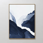 Glacier Flow Canvas Art - Vertical features flowing, layered shapes in deep blue, gray, and white that evoke a mountain or river landscape. Framed in thin gold, this modern decor piece hangs elegantly on a white wall.