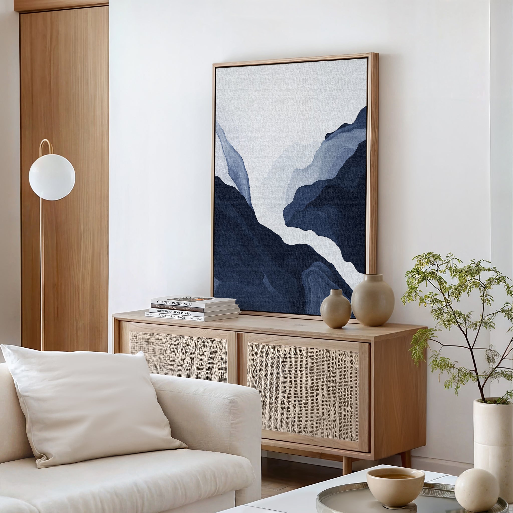 Minimalist living room with the Glacier Flow Canvas Art - Vertical above a rattan sideboard, styled with ceramic vases, stacked books, a globe floor lamp, and a cream sofa for modern home decor.