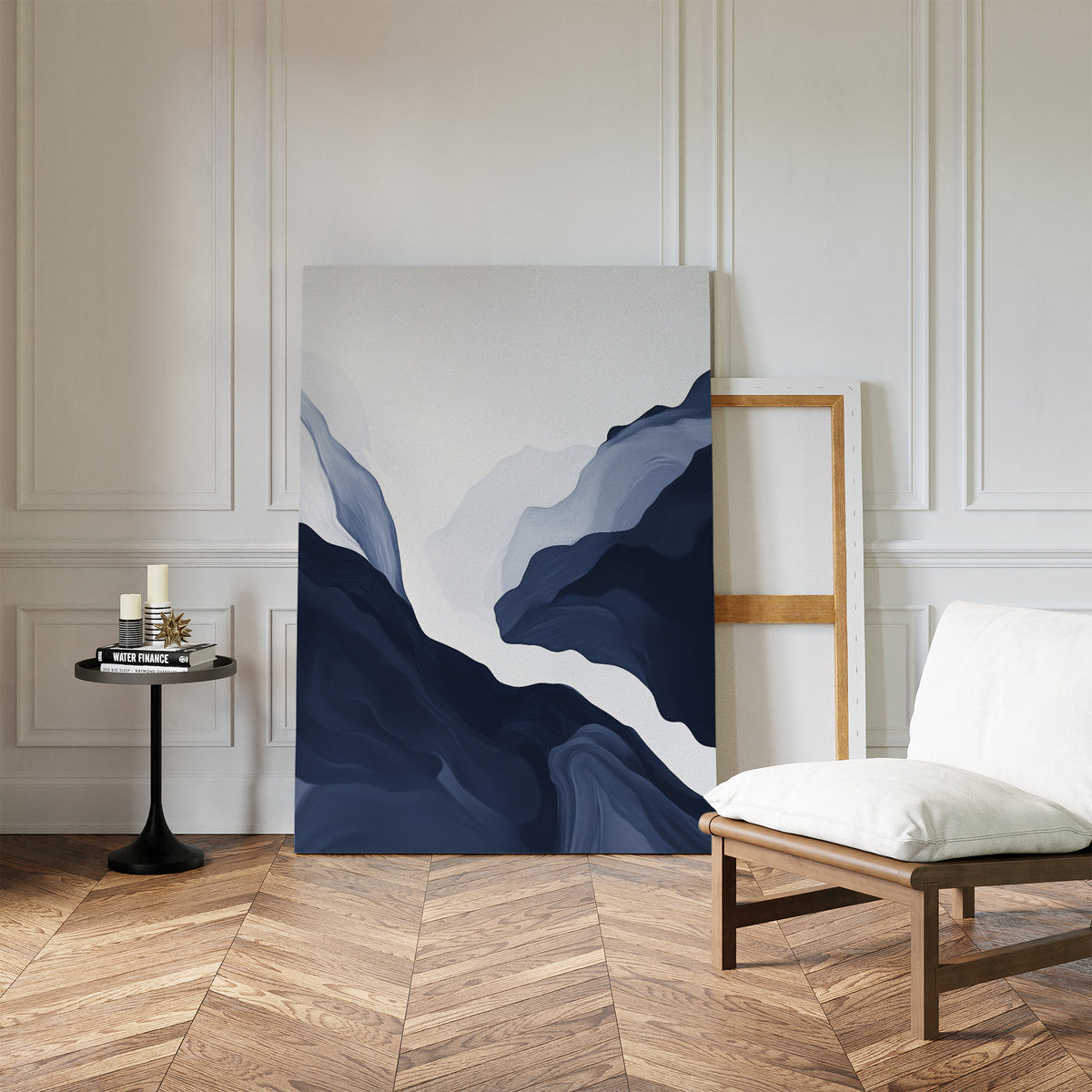 A minimalist room with herringbone wood floors, a white cushioned chair, a black round side table holding candles, and modern decor featuring the Glacier Flow Canvas Art - Vertical leaning against the wall beside an empty frame.
