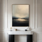 The Golden Fog Horizon Canvas Art - Vertical, with its large moody landscape and muted tones, hangs above a modern console table featuring a white marble top, black legs, and minimalist vases and candles.