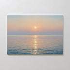 The Golden Reflection Canvas Art - Horizontal features a tranquil ocean at sunrise or sunset, with pastel hues and the sun’s glow on gentle waves, adding serene charm to any plain white wall.