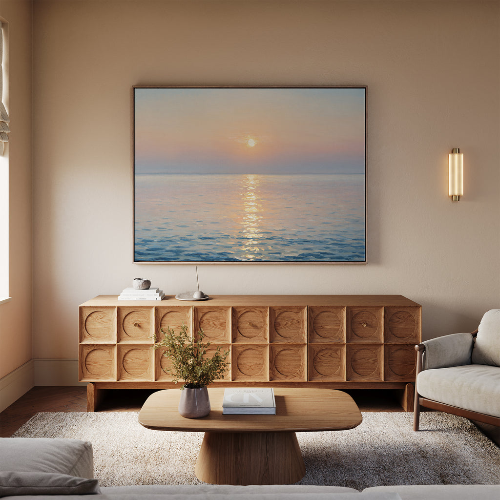 A serene living room with a light wood coffee table, beige sofa, and textured wooden console features the Golden Reflection Canvas Art - Horizontal above the console, casting a warm glow that enhances the inviting, tranquil decor.