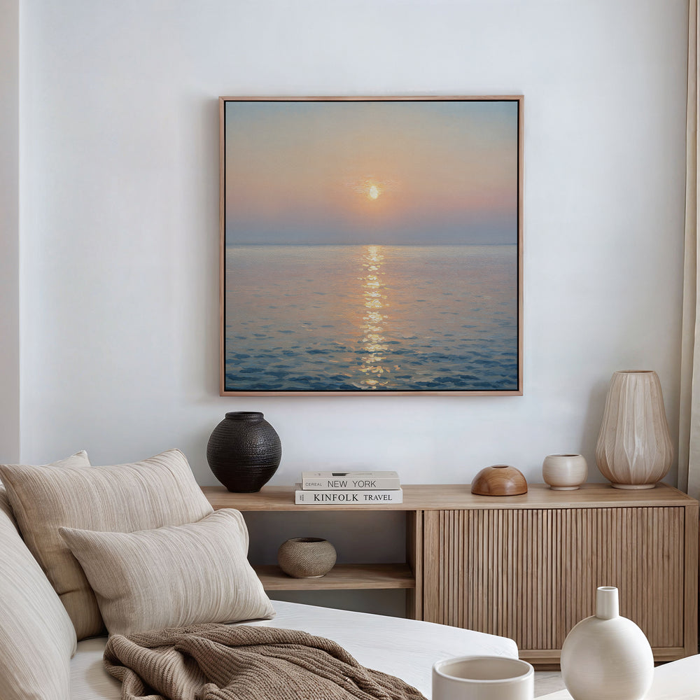 A serene living room showcases a neutral-toned sofa, cushions, and a wooden sideboard with vases and books. Above the sideboard hangs the Golden Reflection Canvas Art - Square, bringing warmth and tranquility to the space.