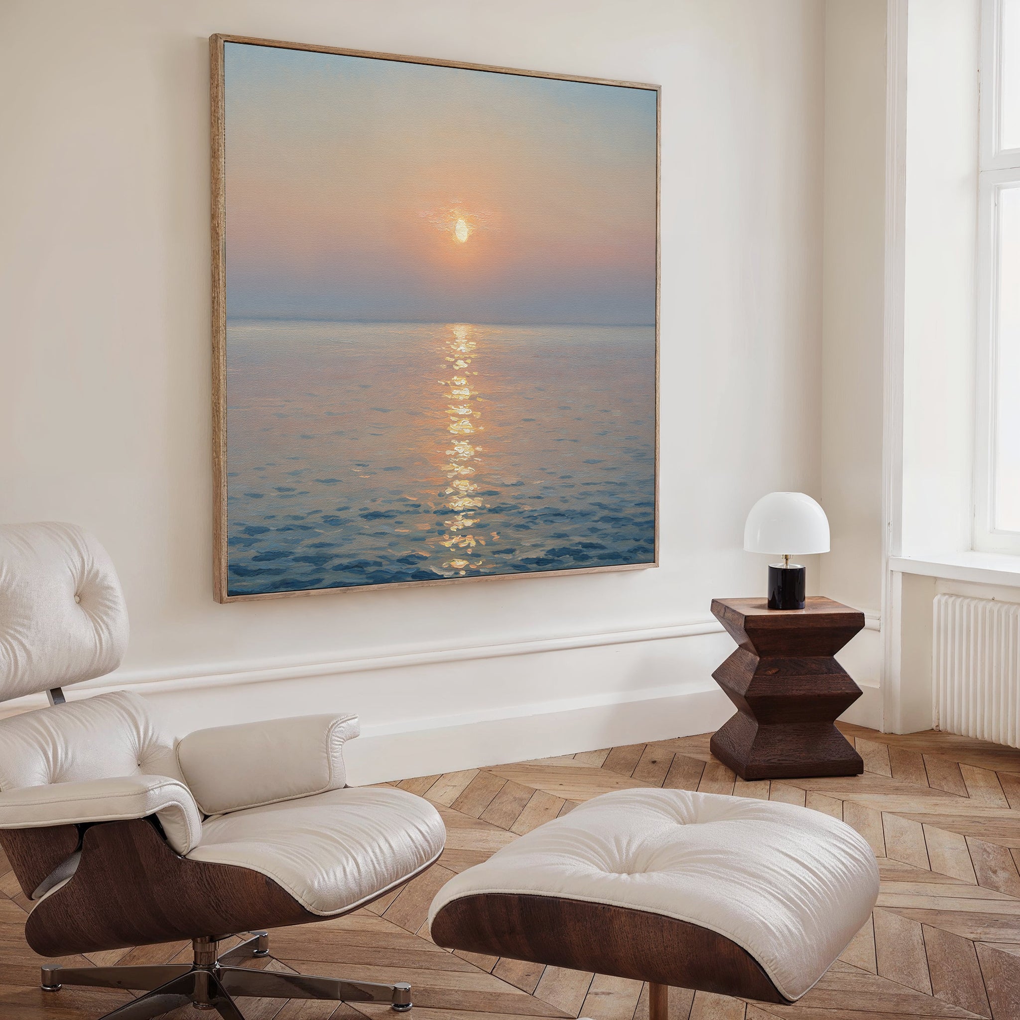 A modern, minimalist room with white walls and wood floors features the Golden Reflection Canvas Art - Square above a white leather lounge chair and ottoman, plus a unique wood side table and small white lamp—perfect for tranquil bedroom decor.