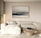 A modern, minimalist living room with a beige sectional sofa, a light wooden coffee table with a black bowl, tall lamp, potted plant, and the Grey Ripples Canvas Art - Horizontal hanging above the sofa.