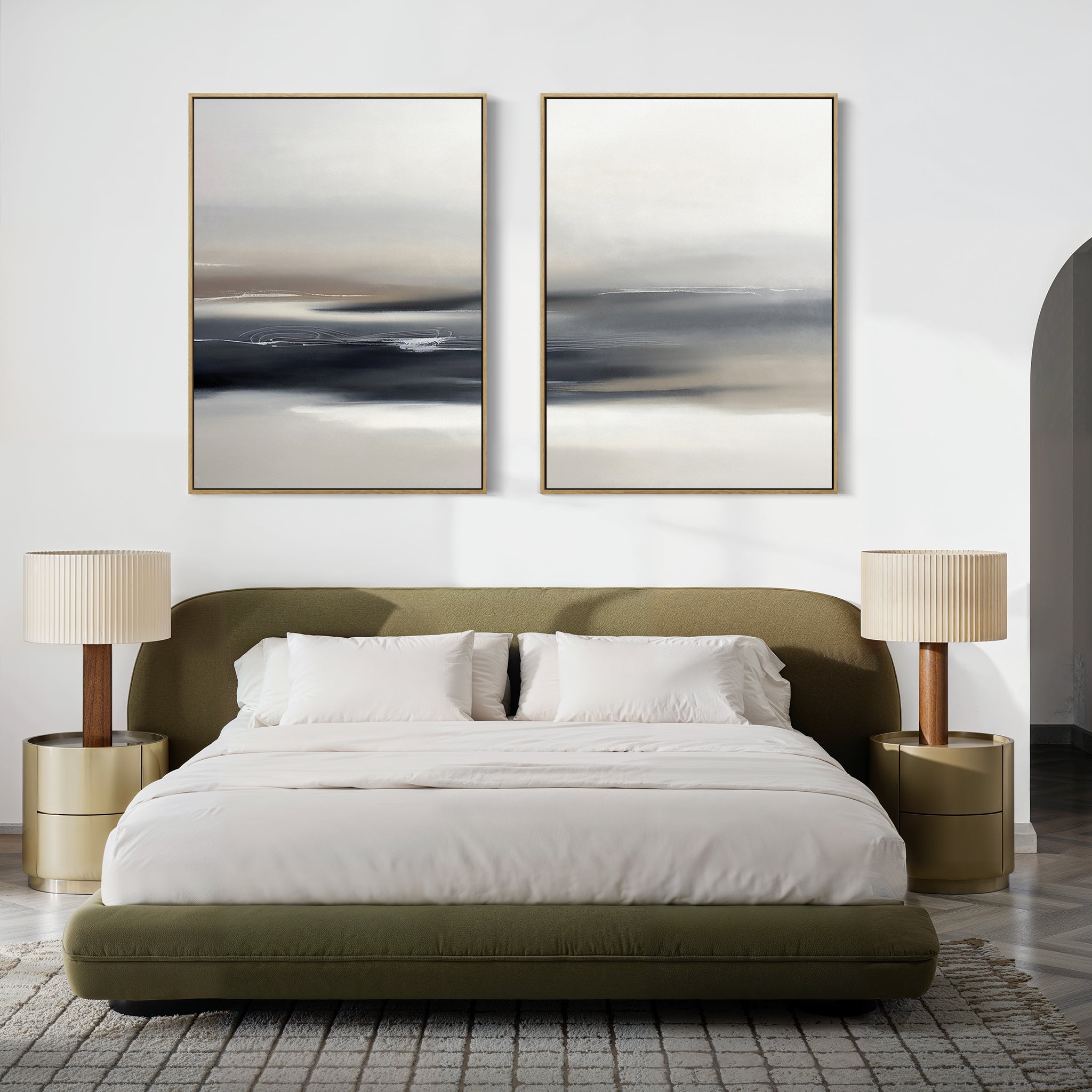 A modern bedroom with an olive-green upholstered bed, white bedding, two gold nightstands with beige lamps, a textured rug, and the "Grey Ripples - Set Of 2" abstract landscape artwork above the bed.