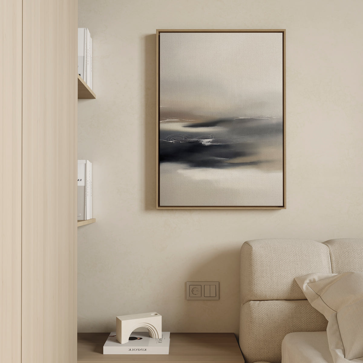 A minimalist living room corner with a beige sofa, shelves with books, a small white geometric decor piece, and the Grey Ripples Canvas Art - Vertical framed and hung on a light-colored wall.