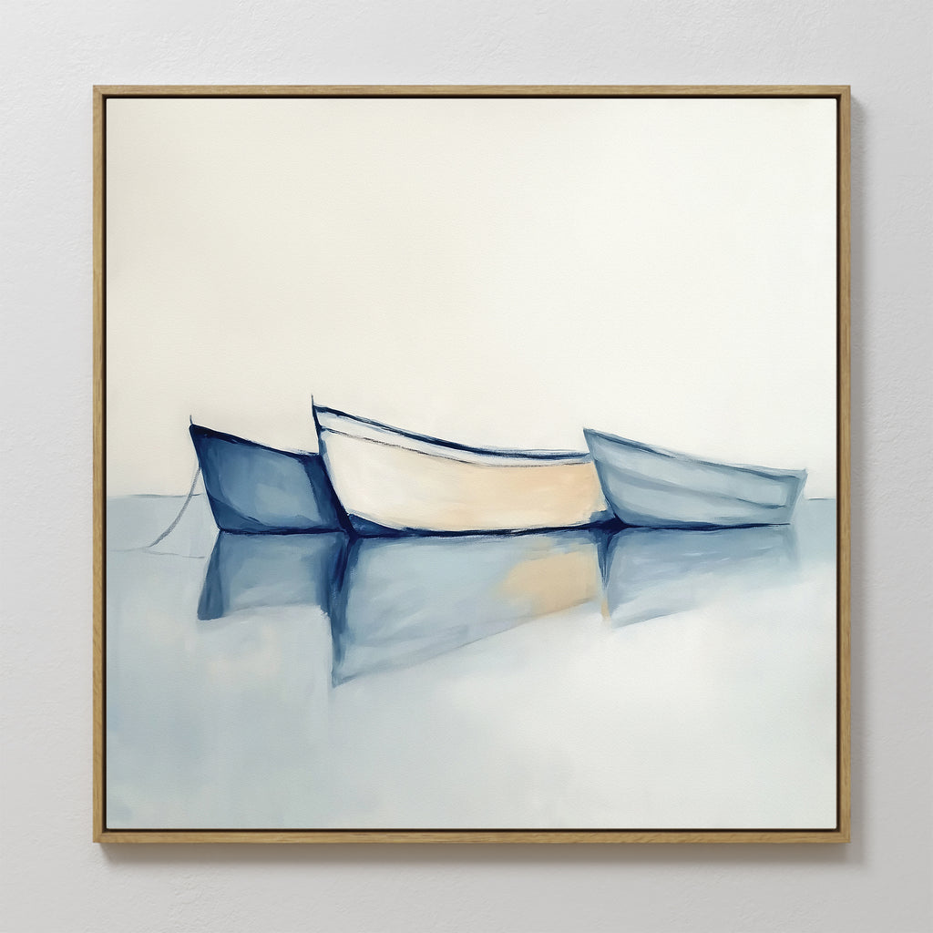 The Harbor Rest Canvas Art - Square features a minimalist scene of three boats—two blue, one white—floating on calm water in soft, muted colors. Finished in a thin gold frame, it adds serene charm to any home decor.