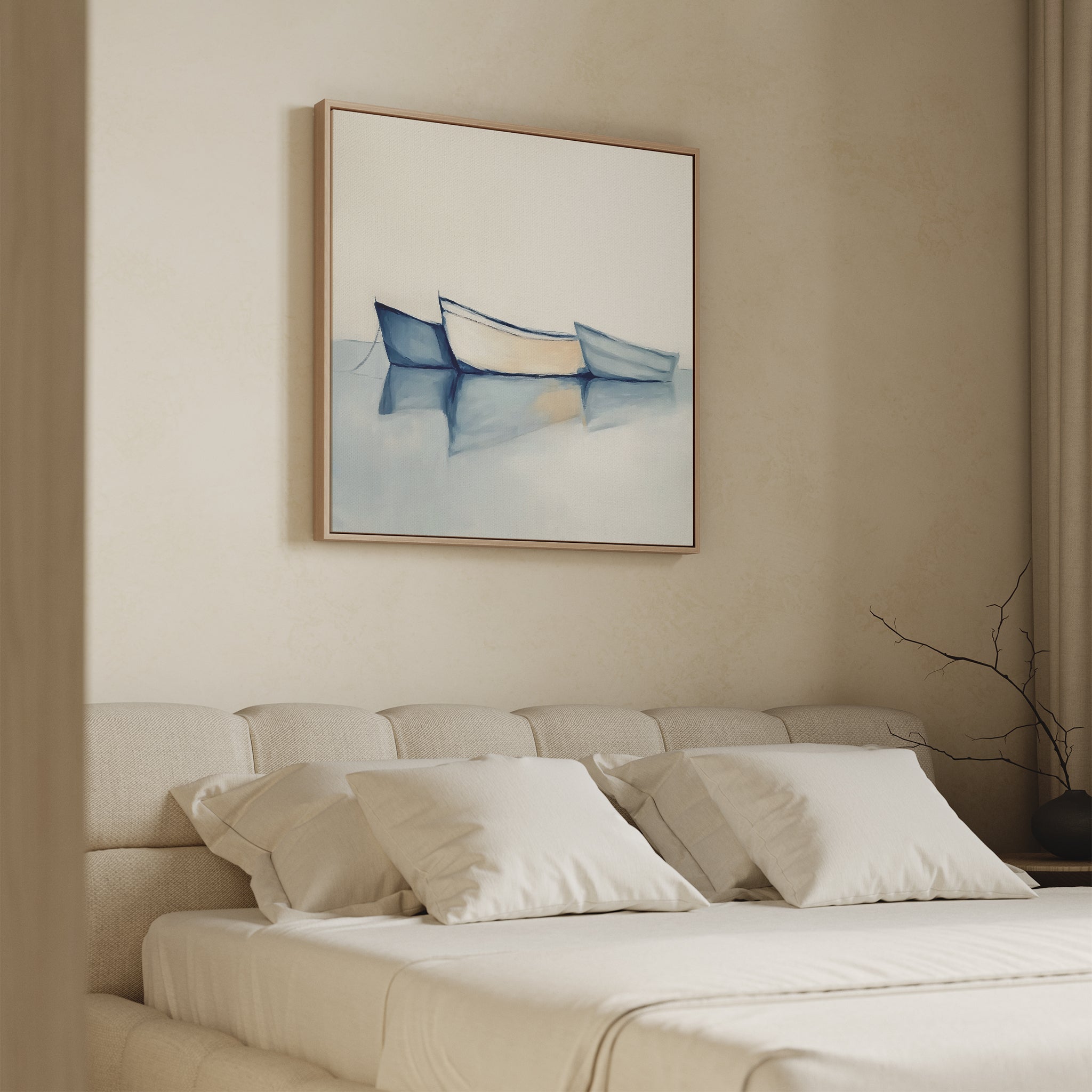 A minimalist bedroom features a beige bed, four white pillows, and the Harbor Rest Canvas Art - Square—a coastal painting of three boats on calm water in soft blue and beige tones—creating a serene, peaceful atmosphere.