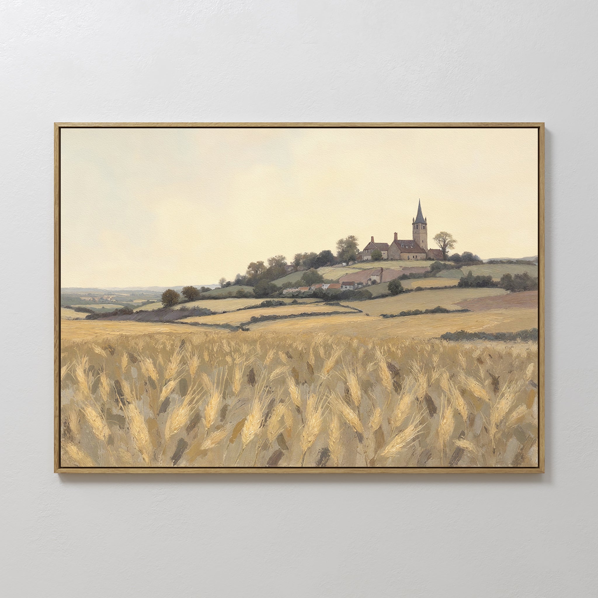 The "Harvest Chapel Canvas Art - Horizontal" is a framed rustic wall art depicting a golden wheat field, rolling hills, and a hilltop church with houses under a pale sky—ideal for pastoral home decor.