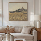 A cozy living room features a beige sofa with neutral cushions, a lamp, and a vase with dried flowers. Above the sofa hangs the "Harvest Chapel Canvas Art - Square," bringing rustic charm to the inviting space.