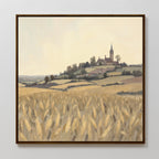 The Harvest Chapel Canvas Art - Square depicts a rustic scene with a wheat field, rolling hills, and the quaint Harvest Chapel nestled among village houses and trees beneath a pale sky.