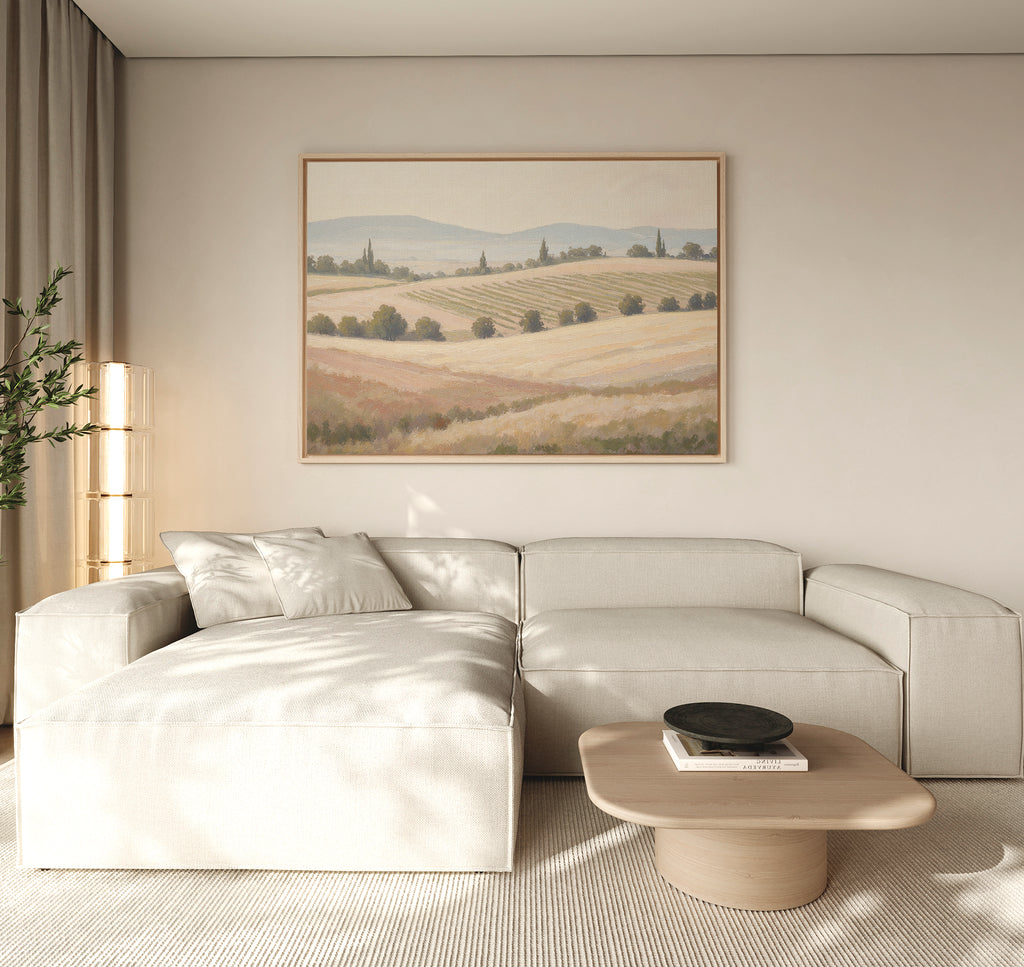 A modern living room with a light beige sectional sofa, wooden coffee table with a black bowl, floor lamp, and Harvest Fields Canvas Art - Horizontal on the wall. Neutral tones create a calm, minimalist atmosphere.