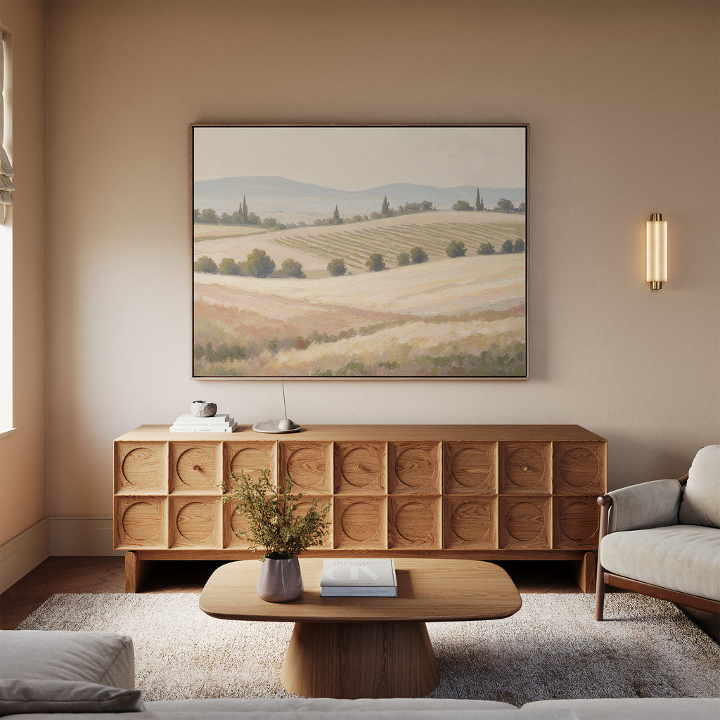 A cozy living room with a light wooden coffee table, matching sideboard, beige sofa, and the Harvest Fields Canvas Art - Horizontal hanging above the sideboard. A vase of flowers decorates the table.