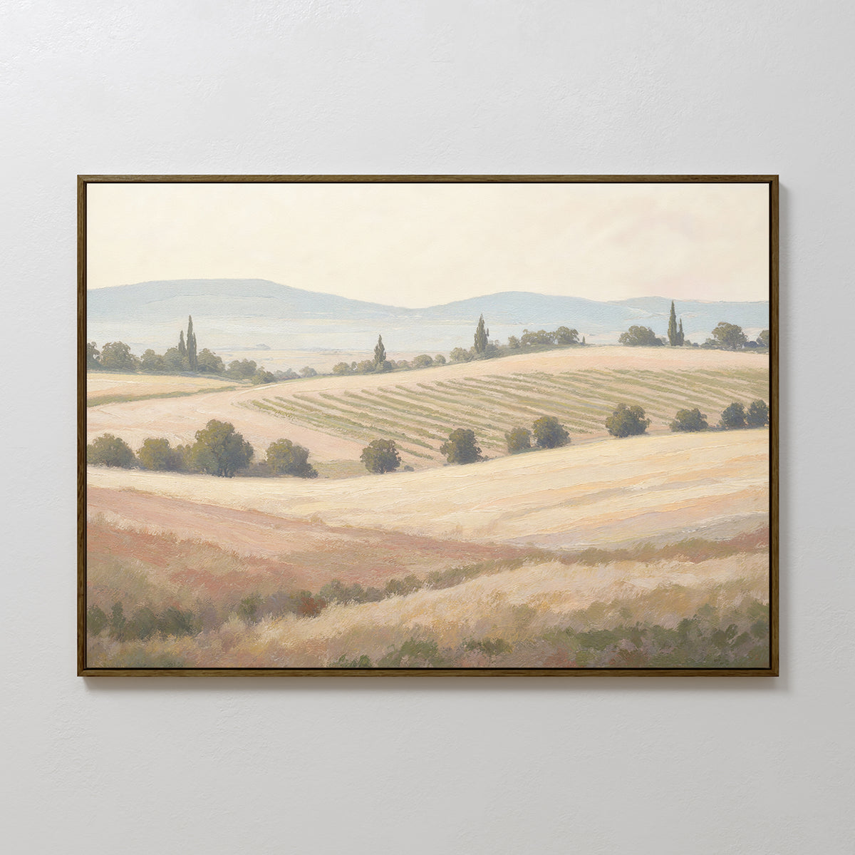 The Harvest Fields Canvas Art - Horizontal is a framed painting depicting a tranquil rural landscape with rolling fields, crops, scattered trees, distant hills, and a softly lit sky.