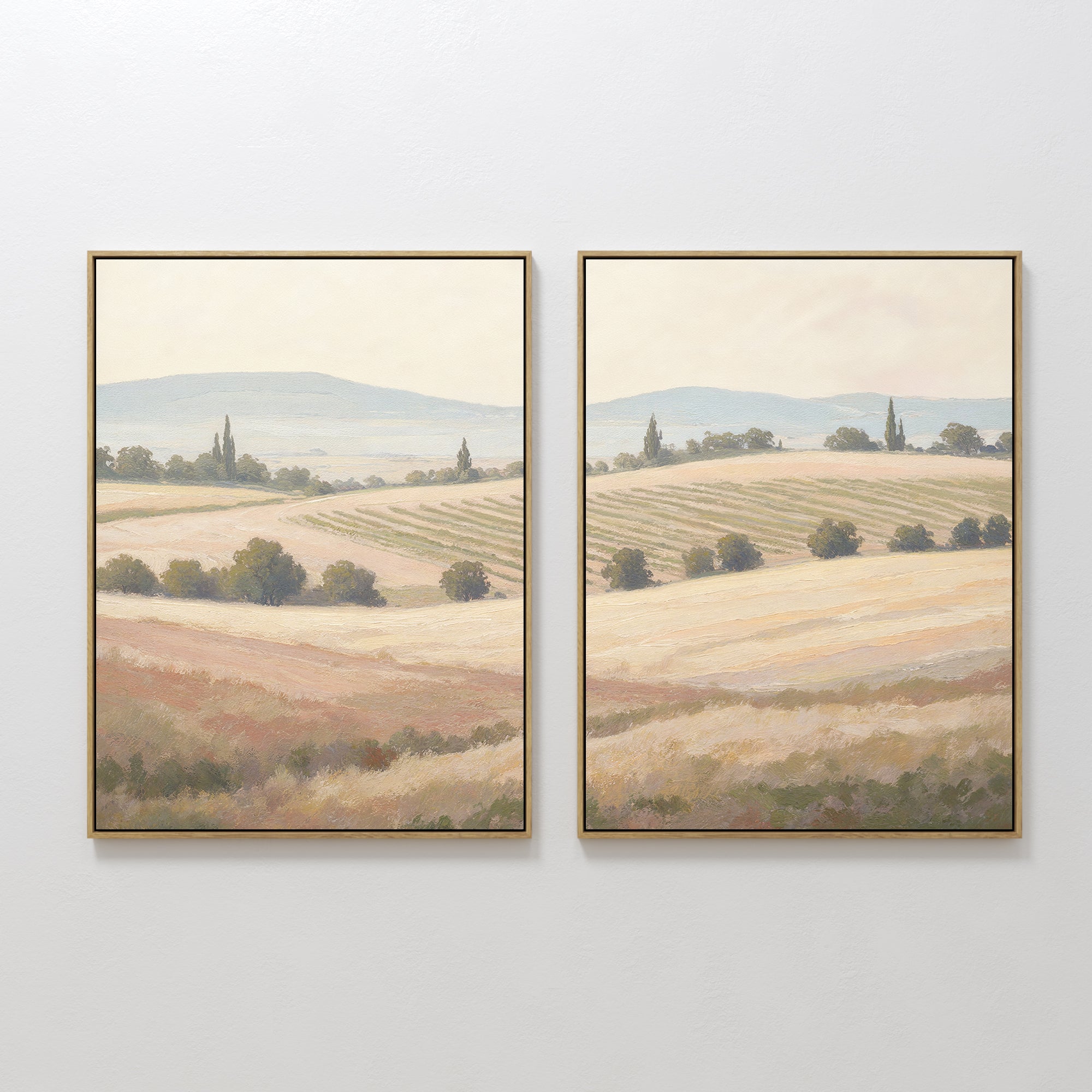 Harvest Fields - Set of 2 features framed paintings of sunlit countryside landscapes with rolling hills and trees in earthy tones—ideal wall art for adding serene farmhouse decor to any white wall.
