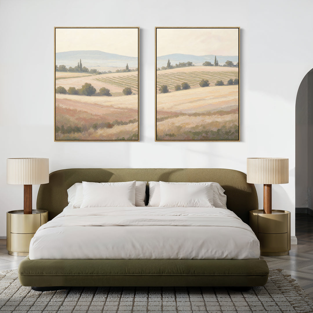 A modern bedroom with an olive-green upholstered bed, white bedding, two gold nightstands with beige lamps, and serene farmhouse decor featuring the "Harvest Fields - Set of 2" pastoral landscape canvas art above the bed.