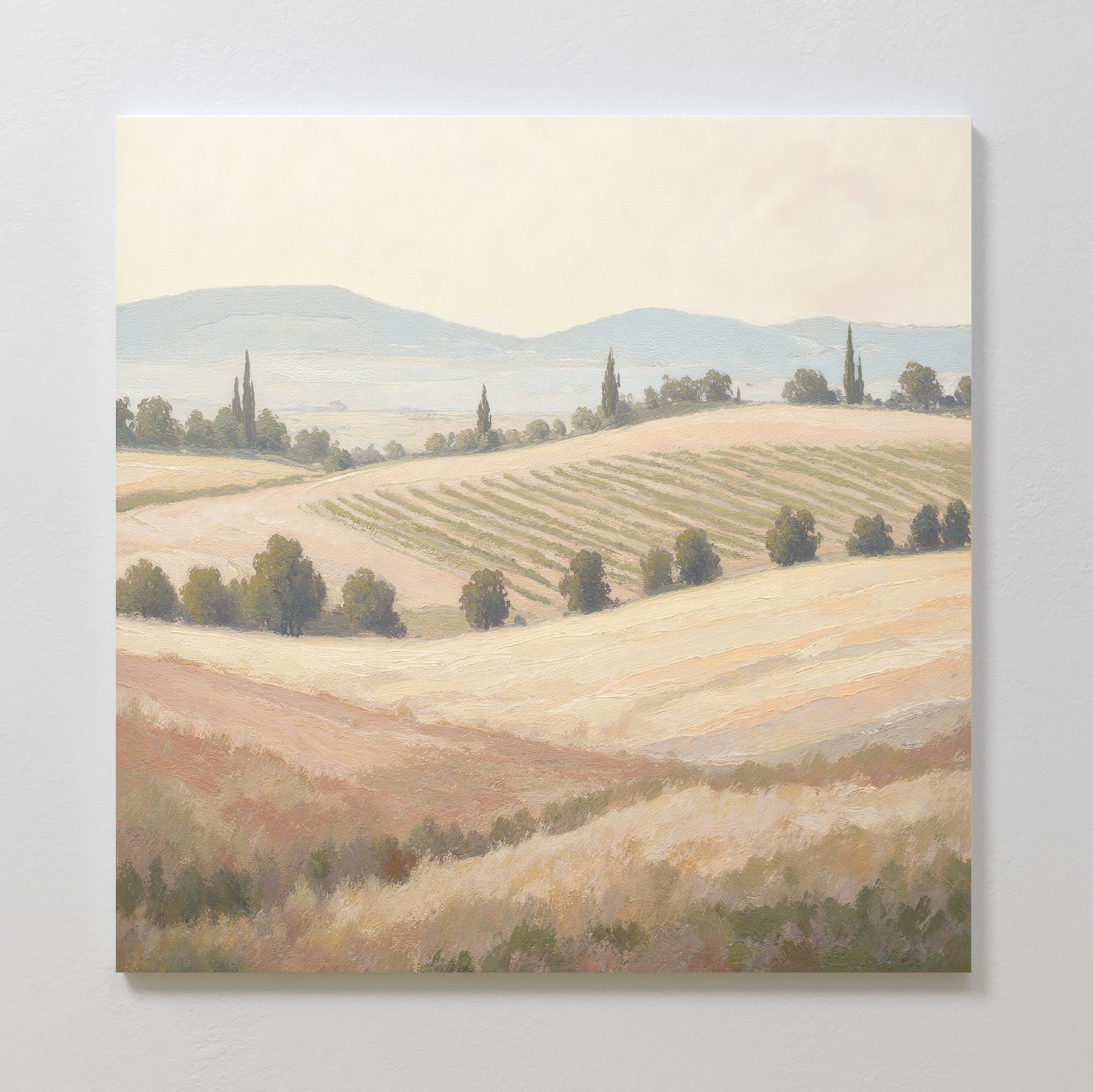 Harvest Fields Canvas Art - Square features a serene countryside scene with rolling hills, golden fields, crops, trees, and distant mountains under a hazy sky—ideal as pastoral wall art or countryside decor.