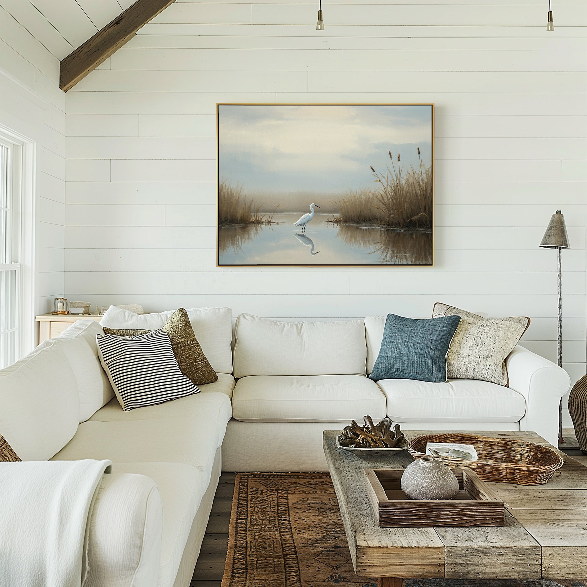 A cozy living room with a white sectional sofa, assorted pillows, wooden coffee table, and the Heron's Morning Canvas Art - Horizontal displayed on a white shiplap wall. Natural light enhances the serene and inviting space.