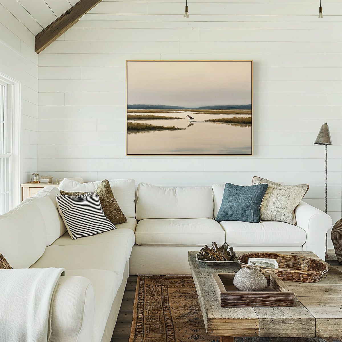 A bright, cozy living room with white shiplap walls, a large white sectional sofa with pillows, a rustic wooden coffee table, and the Marsh Bird Canvas Art - Horizontal hanging above the couch.