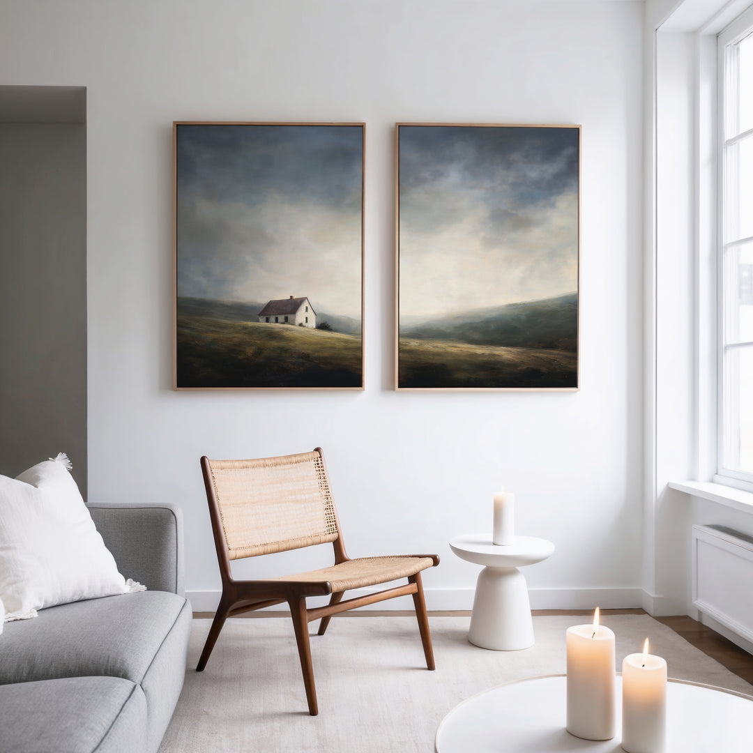 A modern living room with a gray sofa, woven chair, and white side tables. Lit candles add warmth, while the Highland Solitude - Set of 2 canvas prints hang on the white wall near tall windows.
