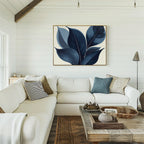 A cozy living room with white walls and a white sofa featuring neutral and patterned pillows. Above the couch hangs the Indigo Depths Canvas Art - Horizontal, adding elegance, while a wooden coffee table sits in front.