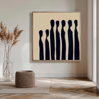 A modern living room showcasing the Indigo Profile Abstract Canvas Art—an abstract painting of elongated black figures on beige—paired with a woven ottoman and clear vase with dried pampas grass on a wooden floor.