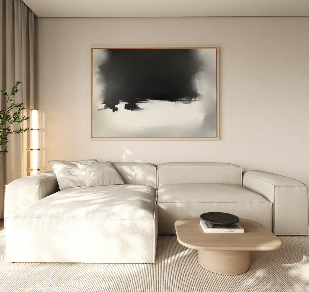 A modern living room featuring a light beige sectional sofa, low wooden coffee table with black bowl, tall lamp, potted plant, and the Ink Cloud Formation Canvas Art - Horizontal adding sophisticated style to the wall.