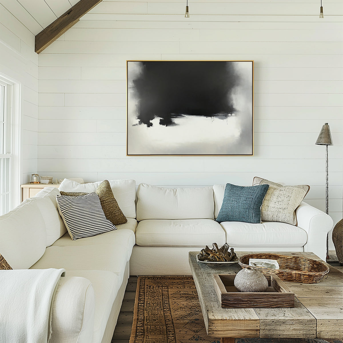 A cozy living room with white shiplap walls, a white sectional sofa, assorted throw pillows, a rustic wood coffee table with trays, and modern flair highlighted by the Ink Cloud Formation Canvas Art - Horizontal above the seating area.