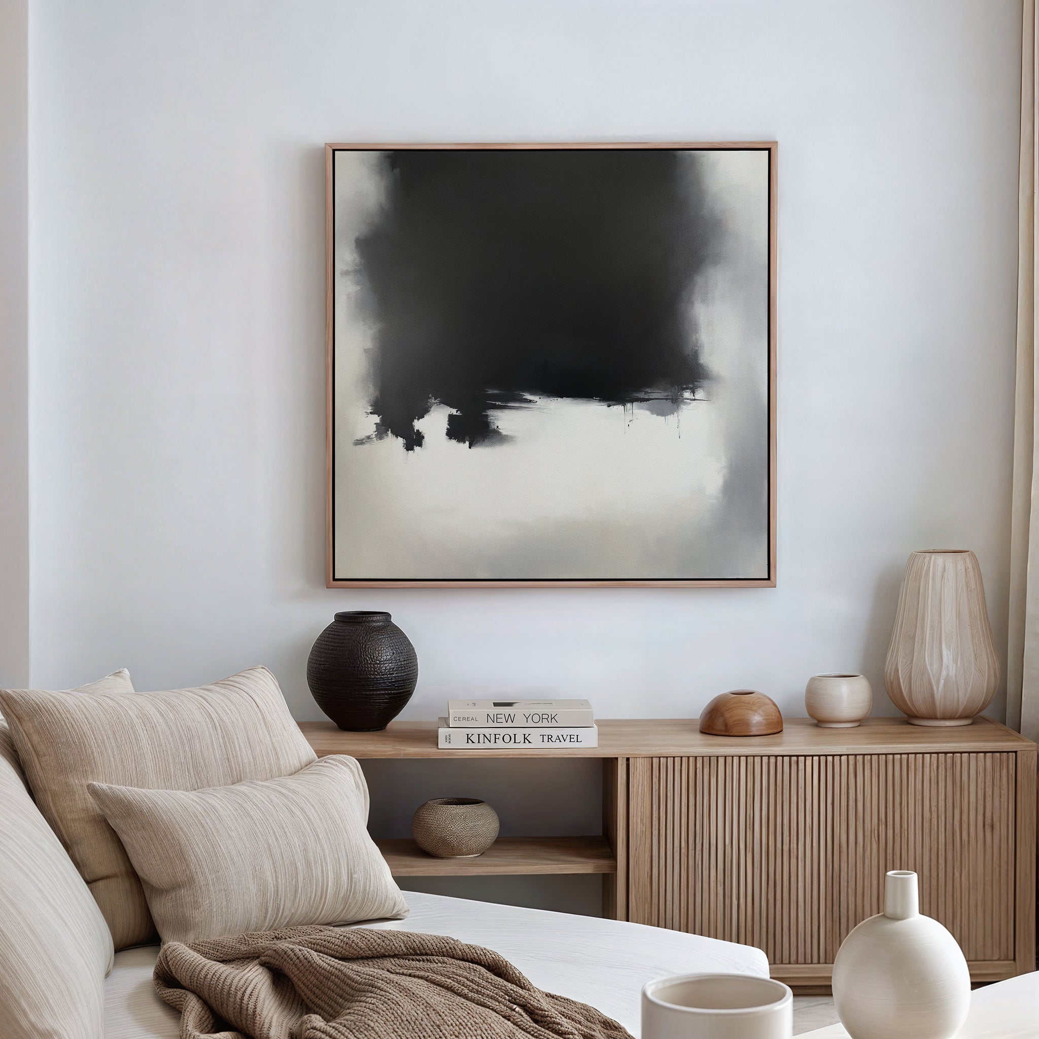 A modern living room features a beige sofa with cushions, a wooden sideboard with books and vases, and the Ink Cloud Formation Canvas Art - Square adding contemporary elegance to the white wall.