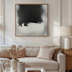 A modern living room features a white sofa, beige cushions, and a wooden side table with a ceramic lamp. Above the couch hangs the Ink Cloud Formation Canvas Art - Square, adding modern flair. A vase with dried flowers rests on the coffee table.