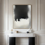 A minimalist entryway features a marble console table, decorative objects, and the Ink Cloud Formation Canvas Art - Vertical on a wall with elegant panel molding for a touch of modern sophistication.