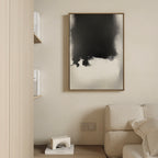 A modern living room features a beige sofa, light wood wall, books on a shelf, and the Ink Cloud Formation Canvas Art - Vertical above a small sculpture, bringing modern sophistication to the cream-colored space.