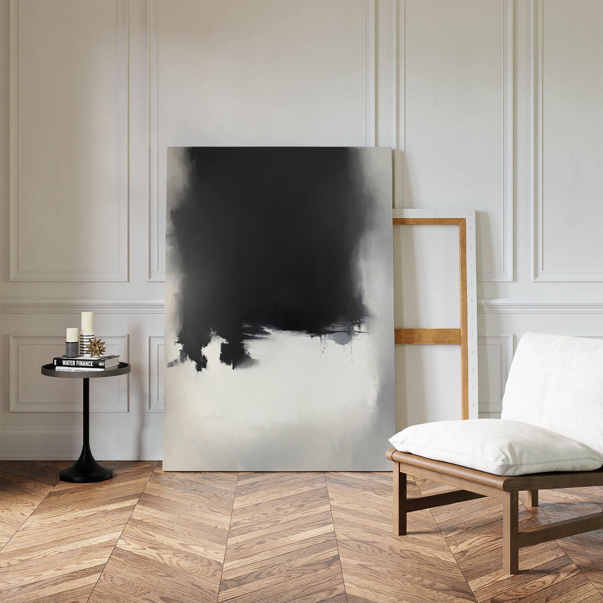 A minimal living room features a white cushioned chair, a round black side table with candles and books, and the Ink Cloud Formation Canvas Art - Vertical leaning against a white paneled wall with parquet wood flooring.