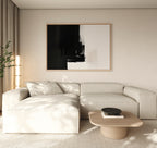 A modern living room features a light beige sectional, a low wooden coffee table, a black bowl, a tall corner plant, and the Ink Divide Canvas Art - Horizontal—a large abstract piece—adding contemporary elegance to the space.