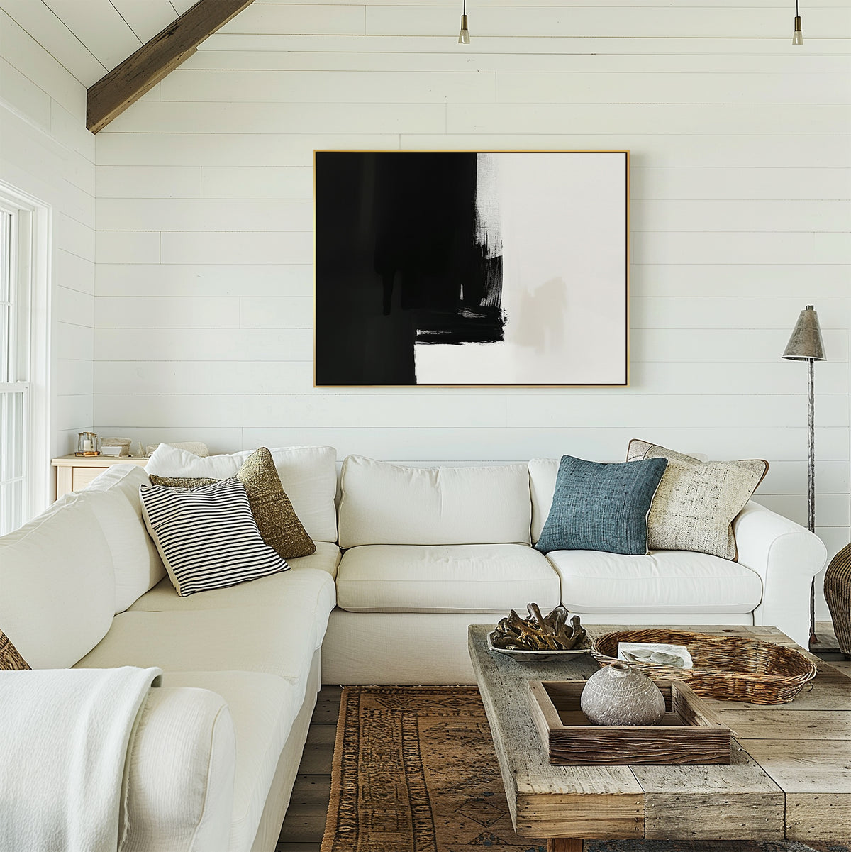 A cozy living room features a white sectional, neutral throw pillows, a rustic wood coffee table, and the Ink Divide Canvas Art - Horizontal as bold wall décor on a shiplap wall, illuminated by natural light from the left.